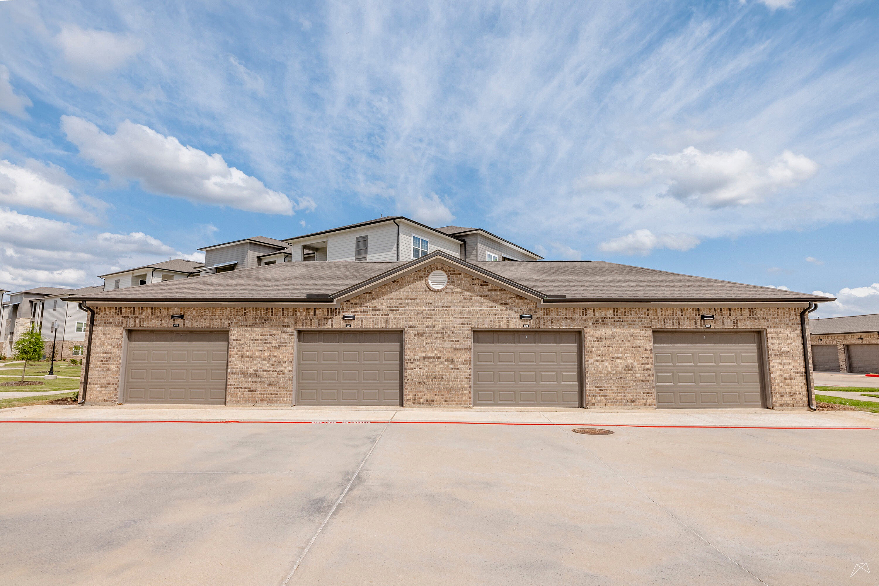 Charming brick garage units under a clear blue sky, providing ample storage and convenience for modern living.