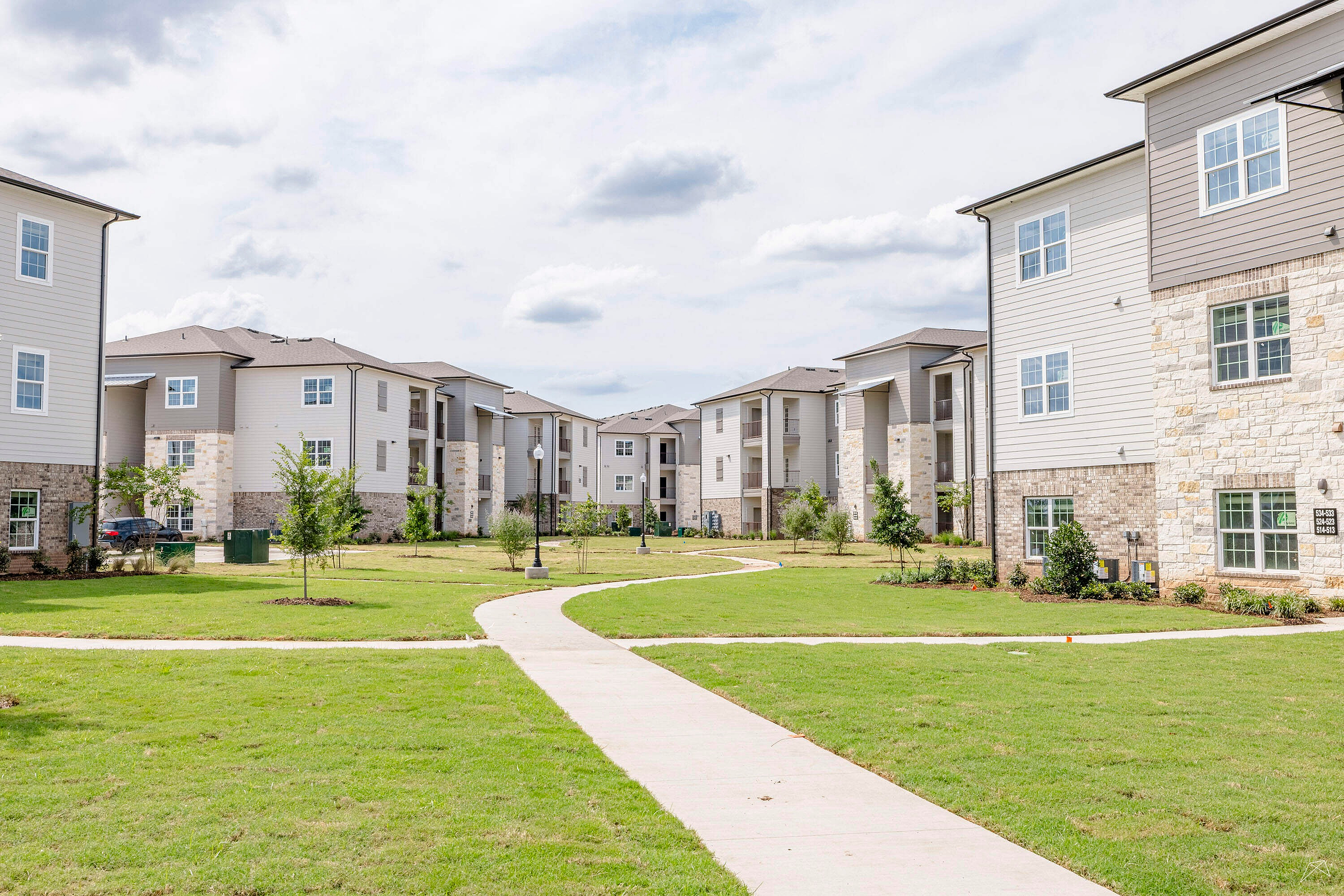 Charming apartment complex nestled in lush greenery, featuring modern architecture and inviting pathways.