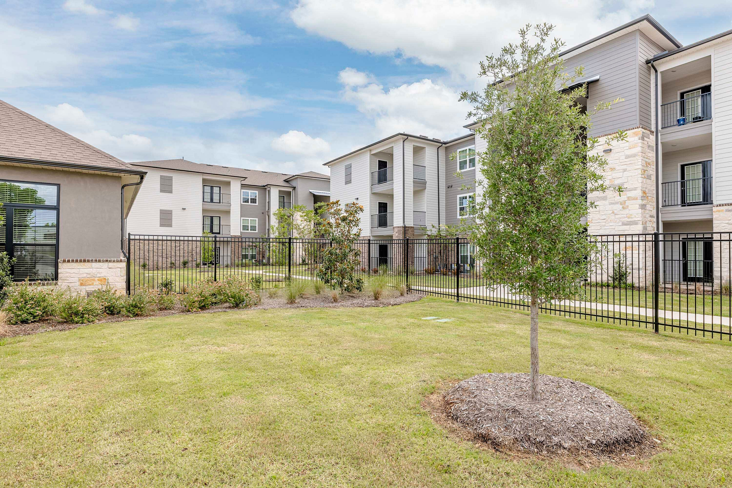 Inviting apartment complex with modern architecture, lush landscaping, and ample outdoor space.