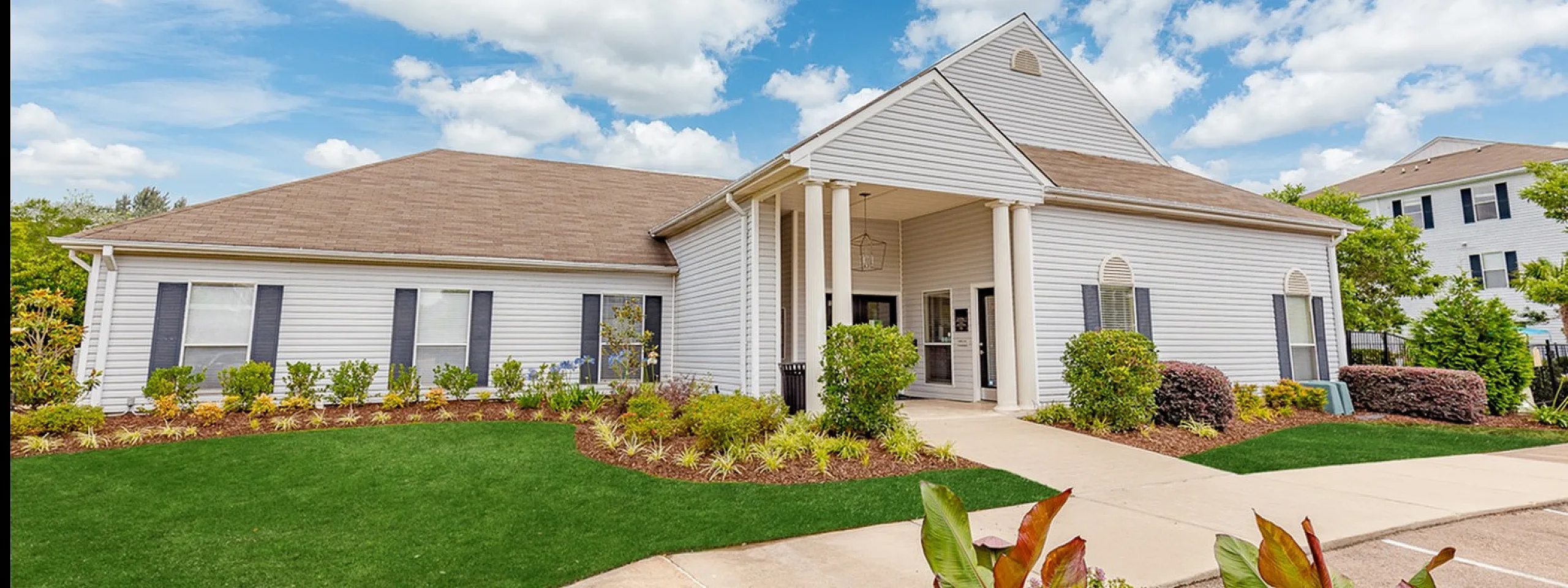 Impressive one-story residential building with well-maintained landscaping under a bright blue sky.