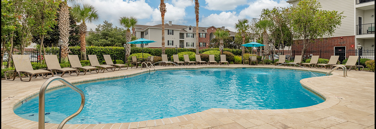 Inviting outdoor swimming pool surrounded by lounge chairs and palm trees under a bright blue sky.