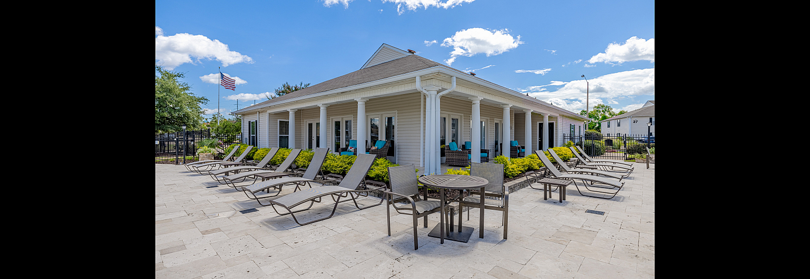 Bright outdoor patio with sun loungers and cozy seating around a stylish building.