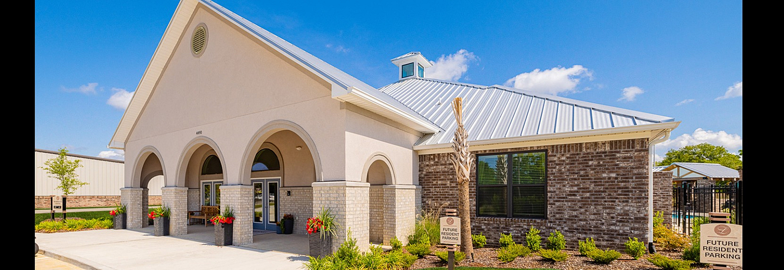 Inviting community center with elegant archways, fresh landscaping, and reserved parking.