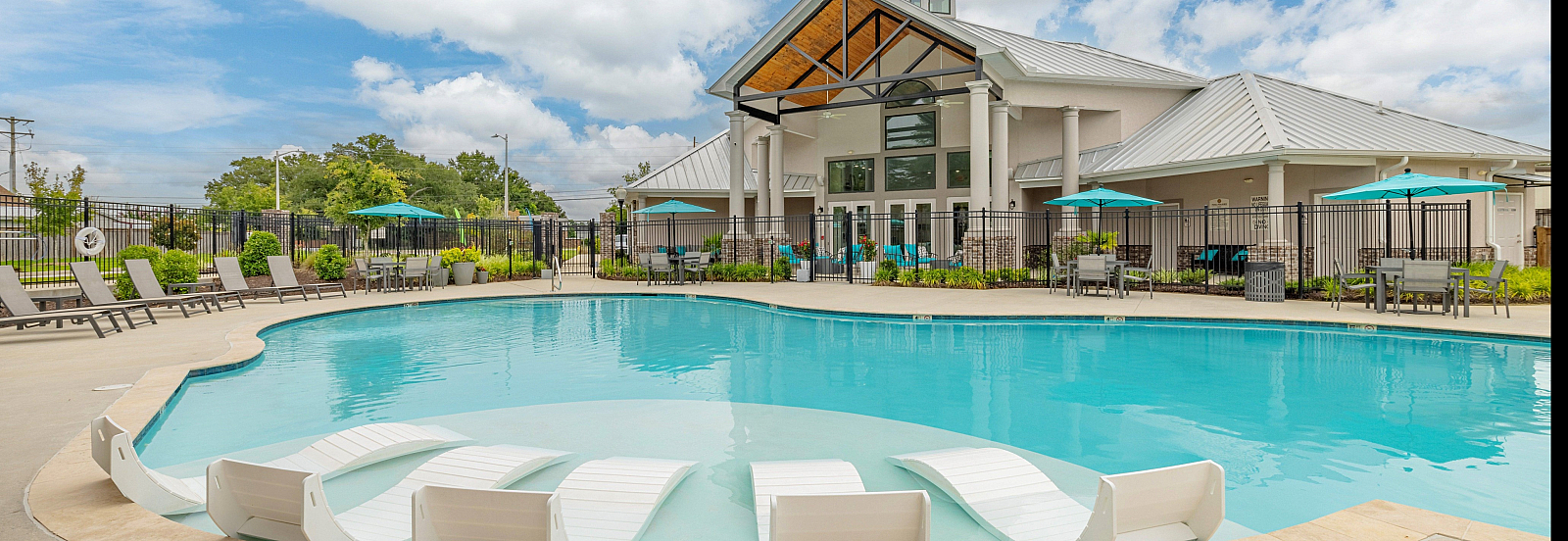 Inviting outdoor pool area with lounge chairs and umbrellas under a blue sky.