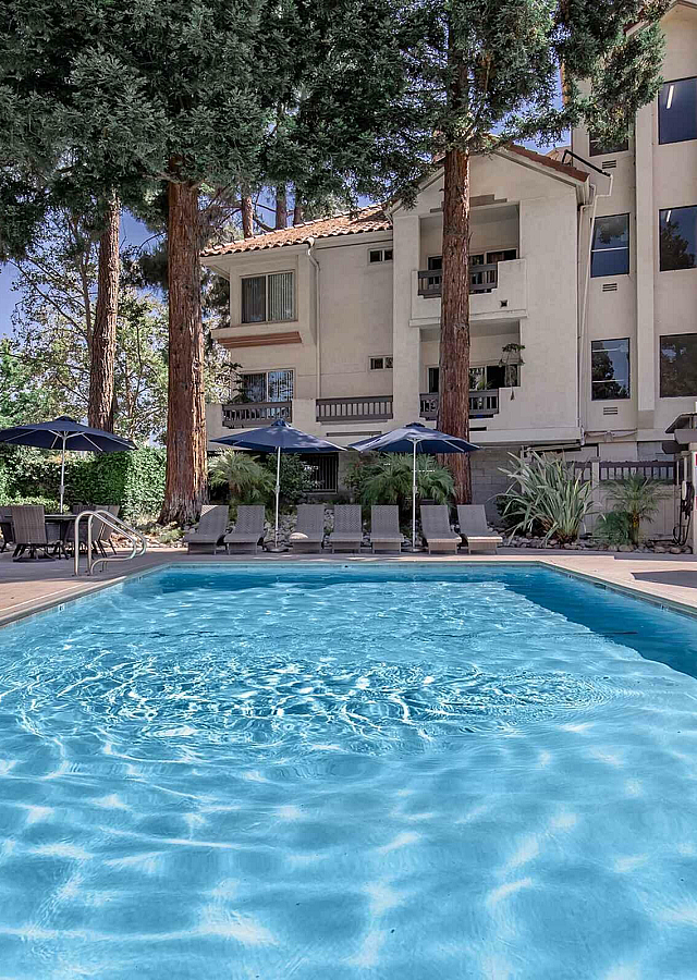 Paloma Vista Apartment Homes Swimming Pool with Lounge Chairs and Blue Umbrellas