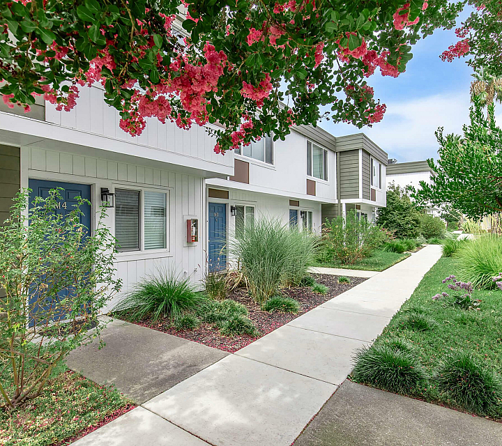 Fairway Village Apartments Building Exterior with Blue Doors and Lush Landscaped Walkway