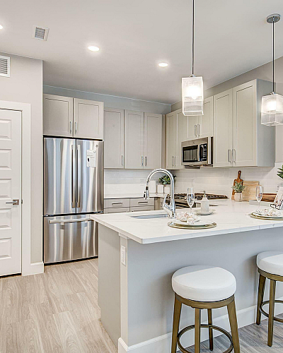 Pr&oacute;ximo at Pe&ntilde;a Station Apartments Modern Kitchen Interiors with Stainless Steel Appliances and Light Gray Cabinetry