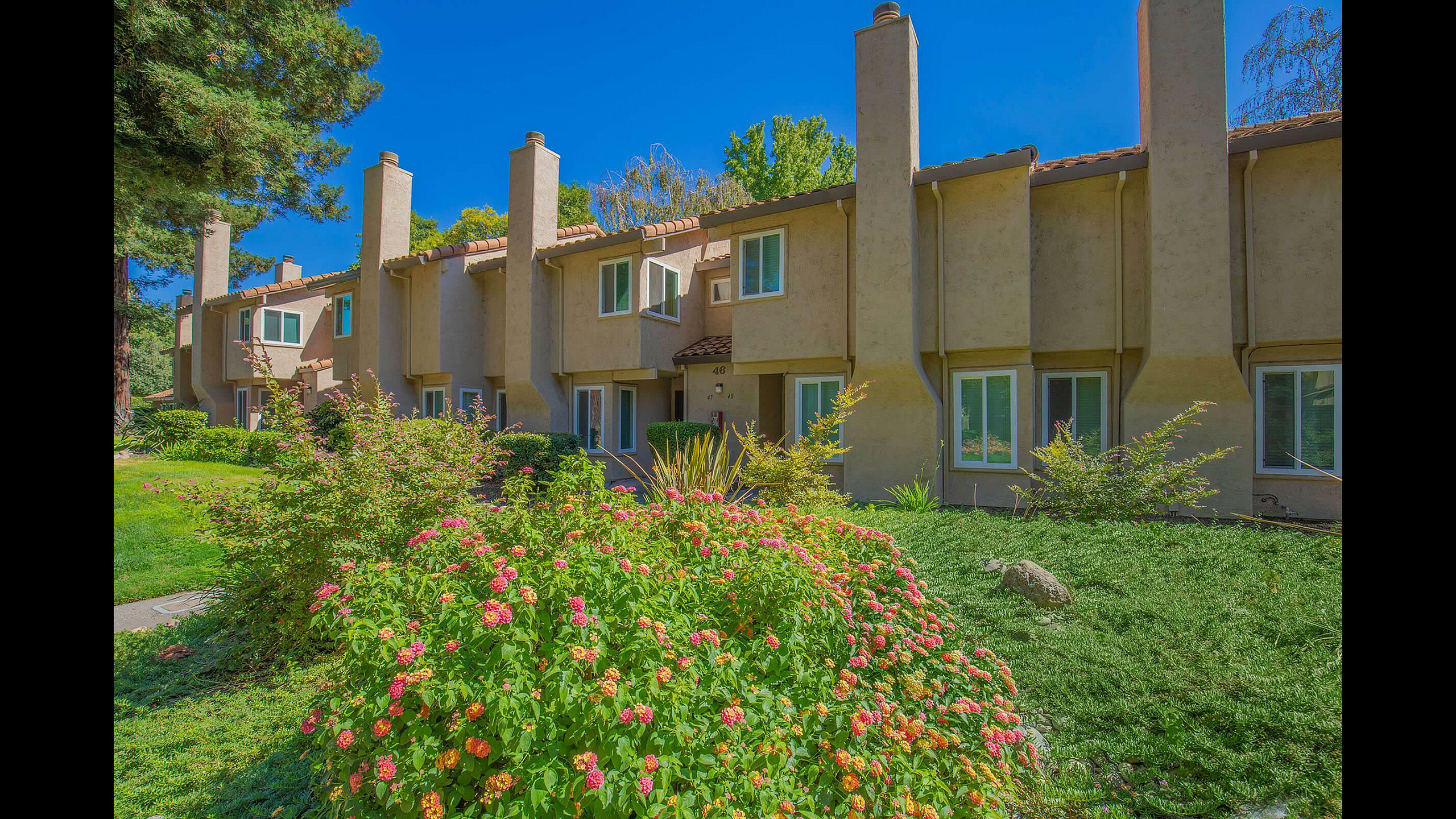 Southwood Townhomes Spanish Style Exterior with Blooming Flowers and Private Entrances