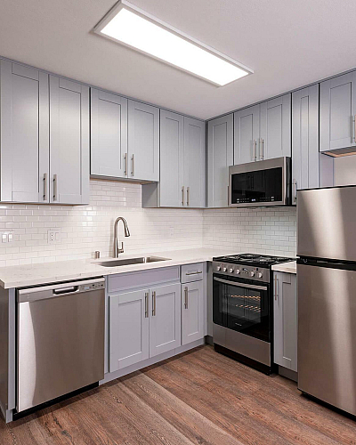 The Hazelwood Kitchen Interior with Gray Shaker Cabinets, Wood Plank Flooring and Stainless Steel Appliances