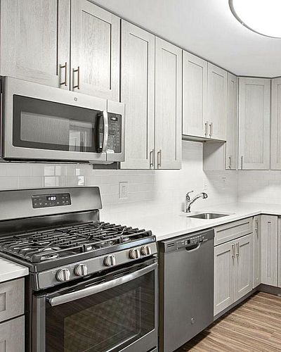 The Oliver in Alexandria Apartments Remodeled Kitchen with Stainless Steel Appliances, Gray Shaker Cabinets and White Countertops, Wood Plank Flooring