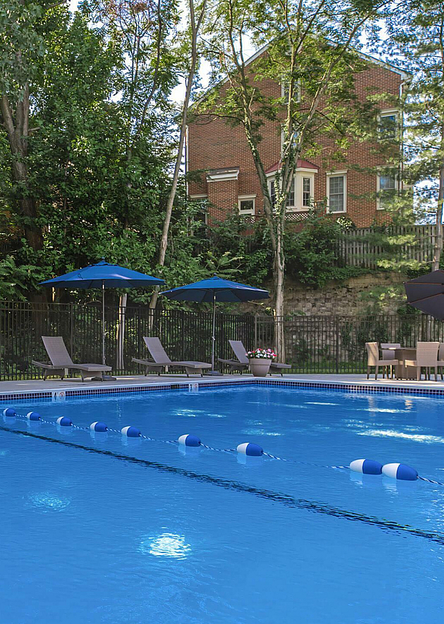 The Oliver in Alexandria Remodeled Swimming Pool with Blue Umbrellas and Comfortable Lounge Seating