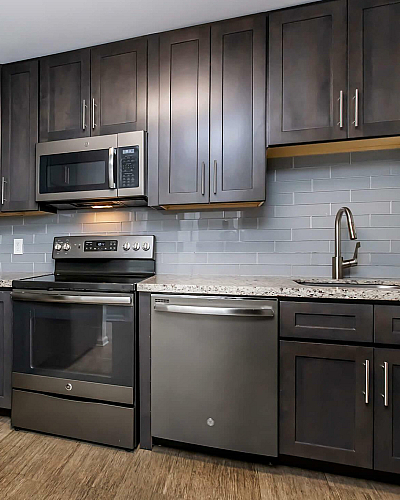 2500 Boca on Federal Apartments Renovated Kitchen Interiors with Dark Cabinetry, Slate Gray Tile Backsplash, Quartz Countertops and Stainless Steel Appliances