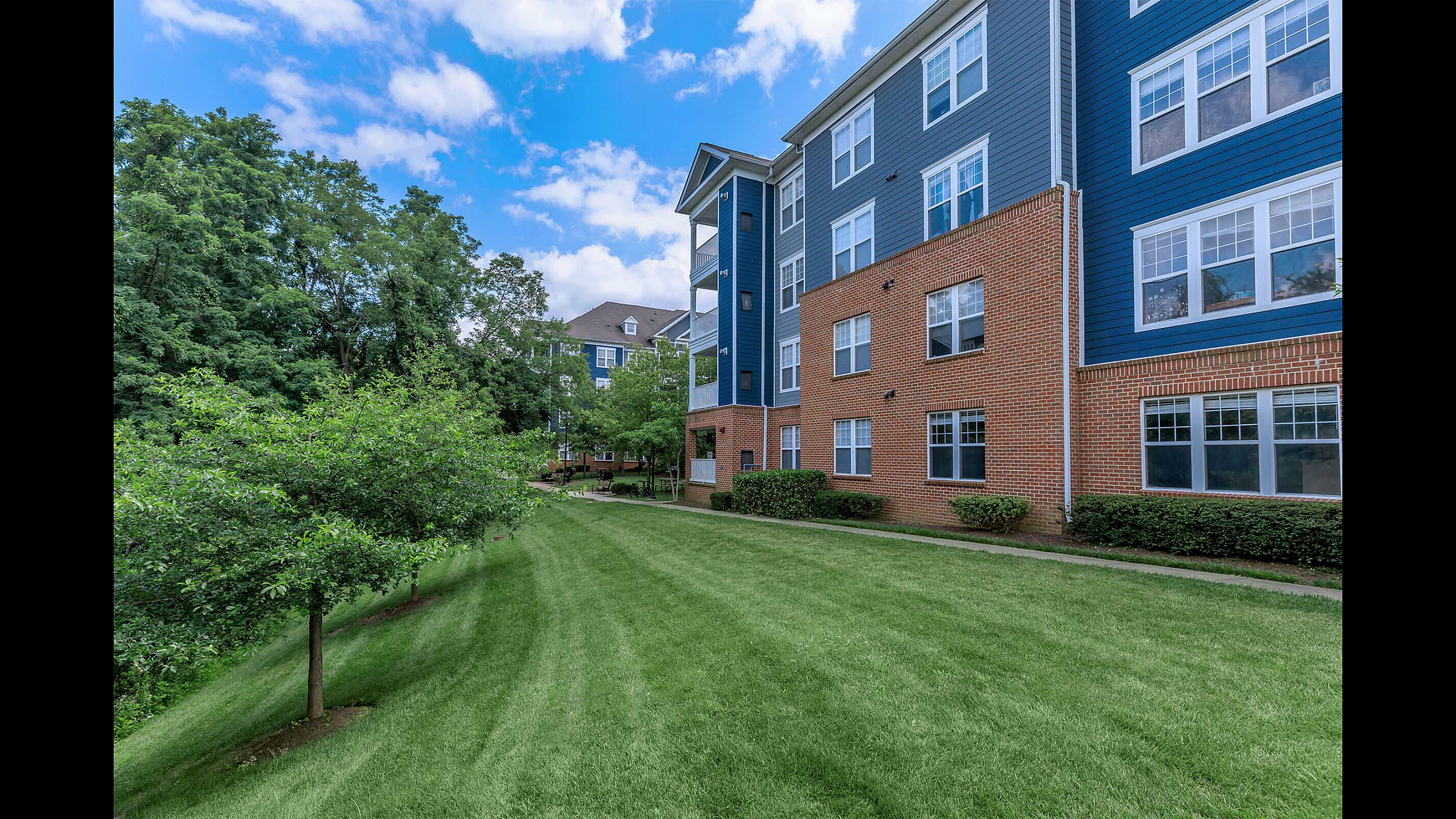 The Rothbury Apartments Blue Siding and Brick Exterior with Lush Landscaping