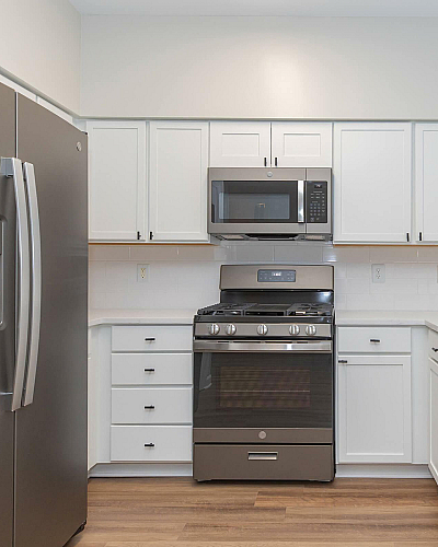 The Rothbury Apartments Kitchen with White Shaker Cabinetry, Stainless Steel Appliances and Wood Plank Flooring