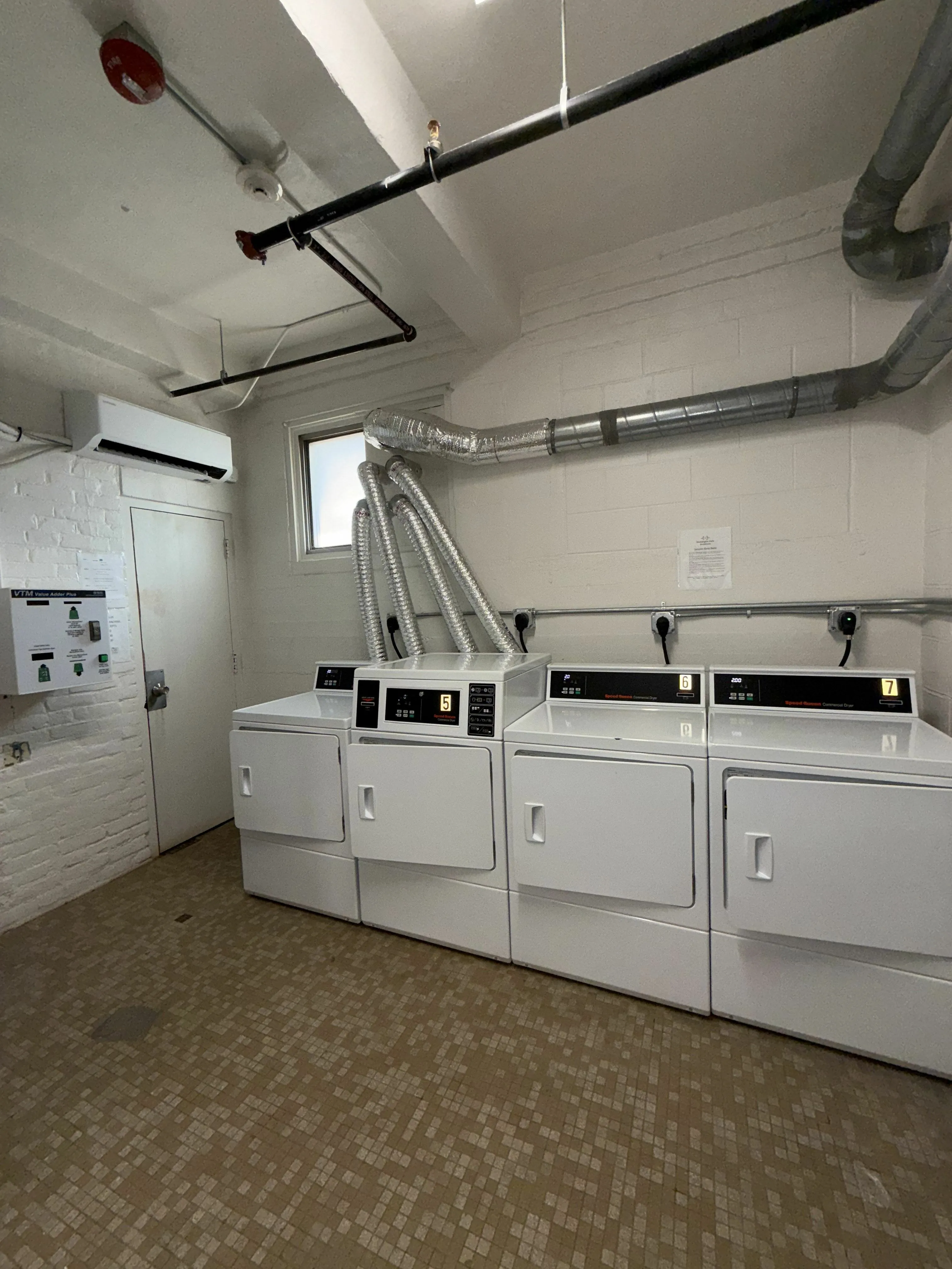 Modern communal laundry room featuring top-loading washers and front-loading dryers for your convenience.