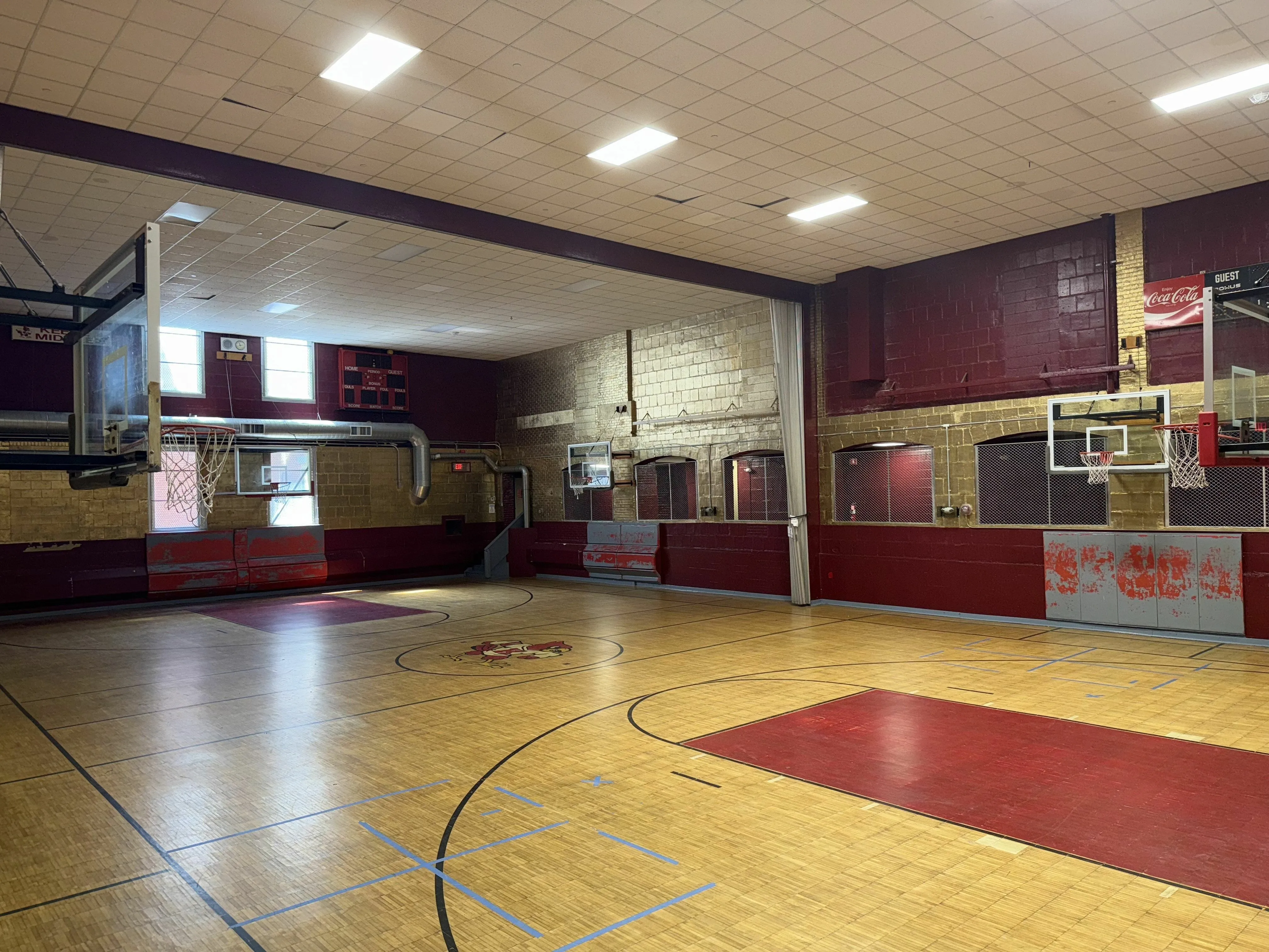 Charming vintage-style indoor basketball court with a classic wooden floor and vibrant red accents, perfect for sports enthusiasts.