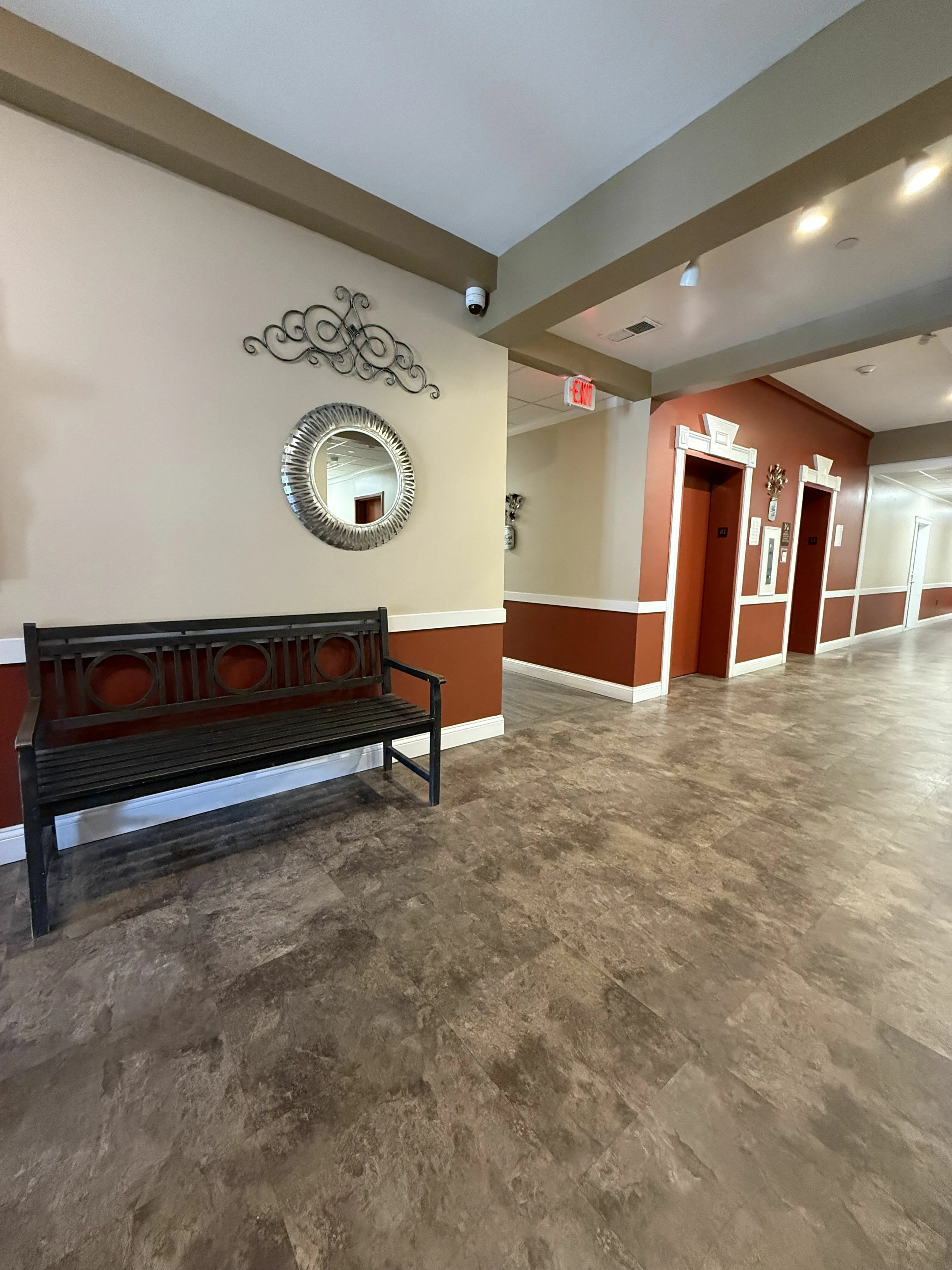 Inviting apartment hallway with elegant wall decor, polished stone flooring, and cozy wooden bench.
