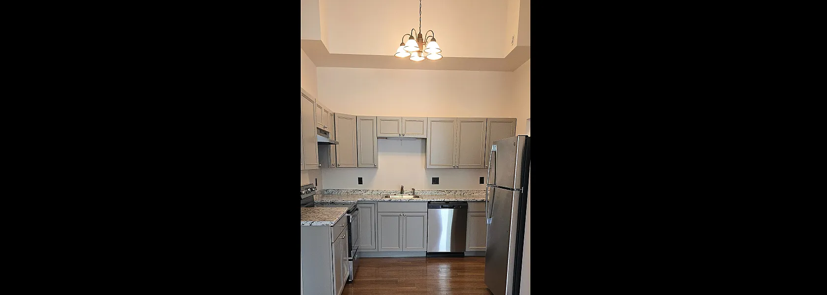 Elegant kitchen with modern stainless steel appliances, chic gray cabinetry, granite countertops, and warm wooden floors.