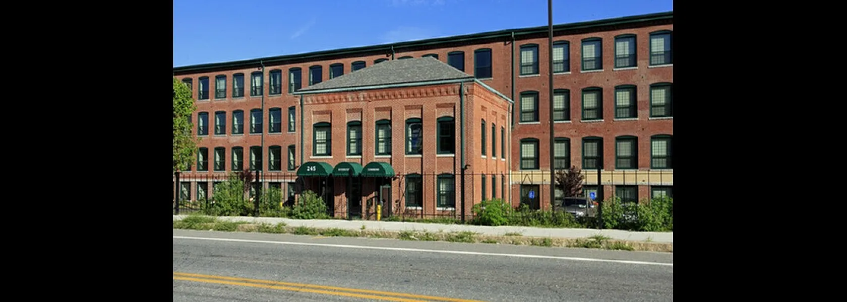Charming red brick apartment building with green awnings, offering a blend of historic charm and modern living.