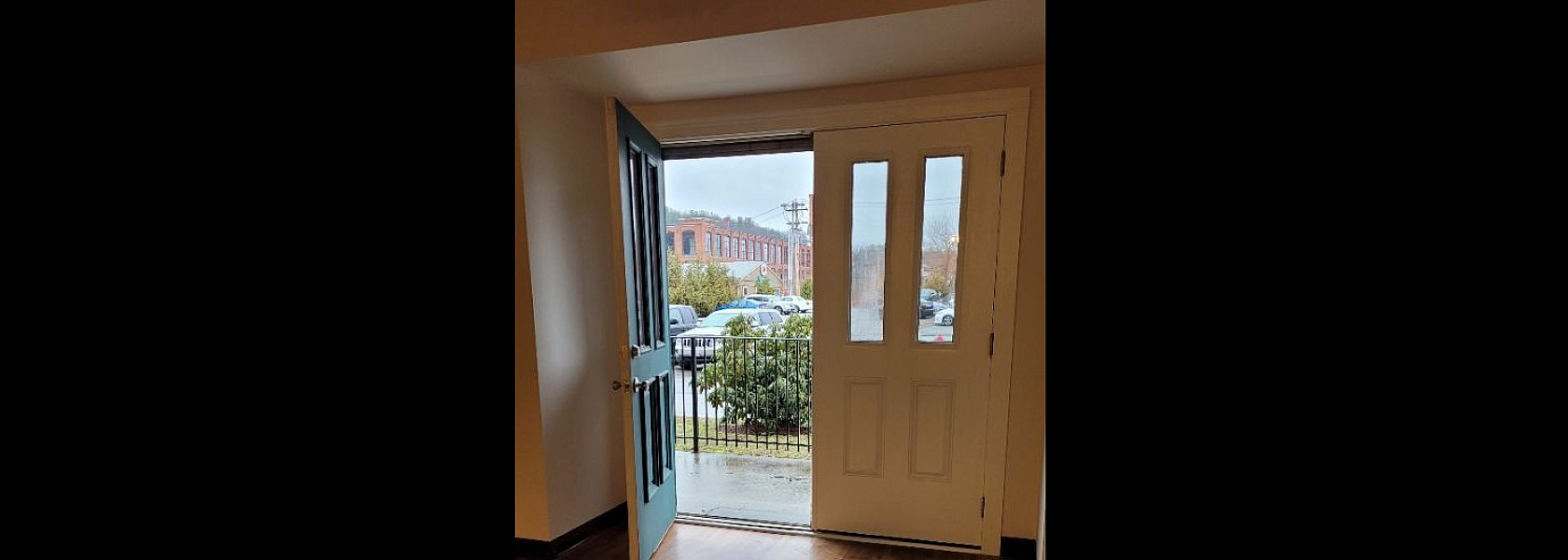 Inviting apartment entrance with elegant wooden flooring and a view of the charming urban landscape outside.