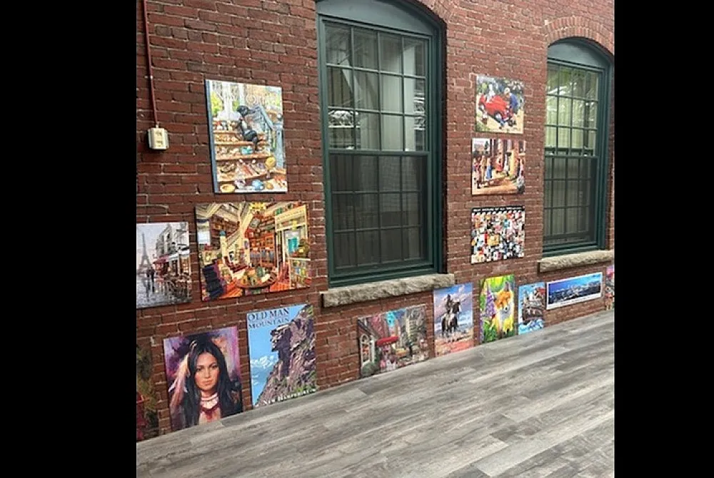 Charming brick wall gallery with vibrant artwork displayed beneath large windows, creating an inviting and artistic atmosphere.