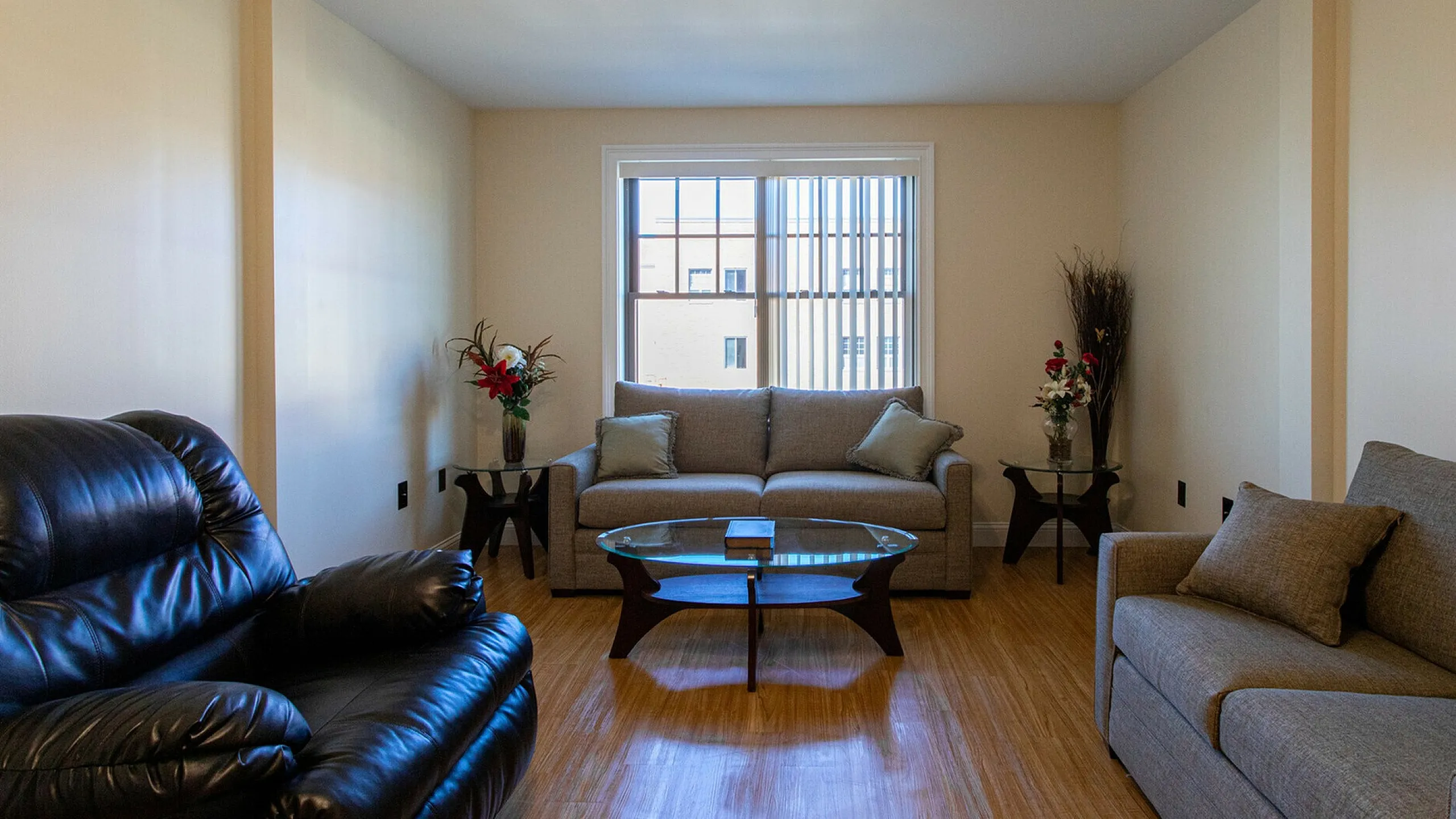 Inviting living room with elegant sofas, a sleek glass coffee table, and vibrant decor, bathed in natural light.
