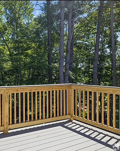 Charming wooden deck with serene forest views, perfect for relaxation and outdoor gatherings.