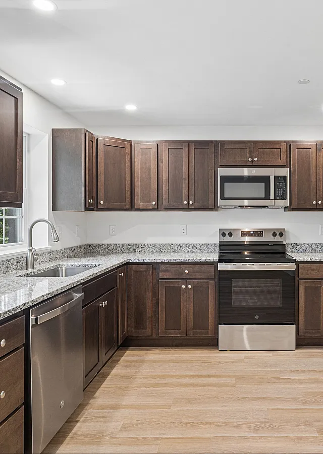 Modern kitchen with sleek stainless steel appliances, rich wooden cabinets, and elegant granite countertops.