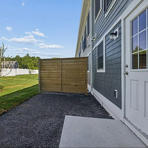 Charming backyard view showcasing a lush green lawn, sleek modern siding, and elegant wooden privacy fence, perfect for serene outdoor relaxation.
