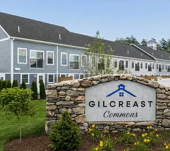 Inviting view of Gilcreast Commons showcasing charming stone signage, elegant architecture, and lush landscaping.