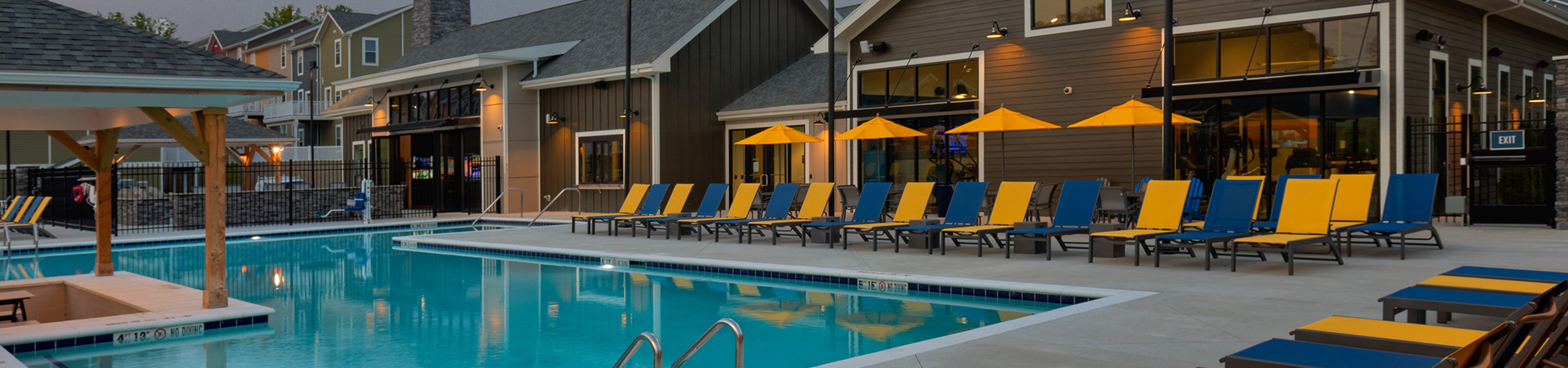 Inviting outdoor pool area with vibrant yellow and blue lounge chairs, perfect for relaxation and leisure.