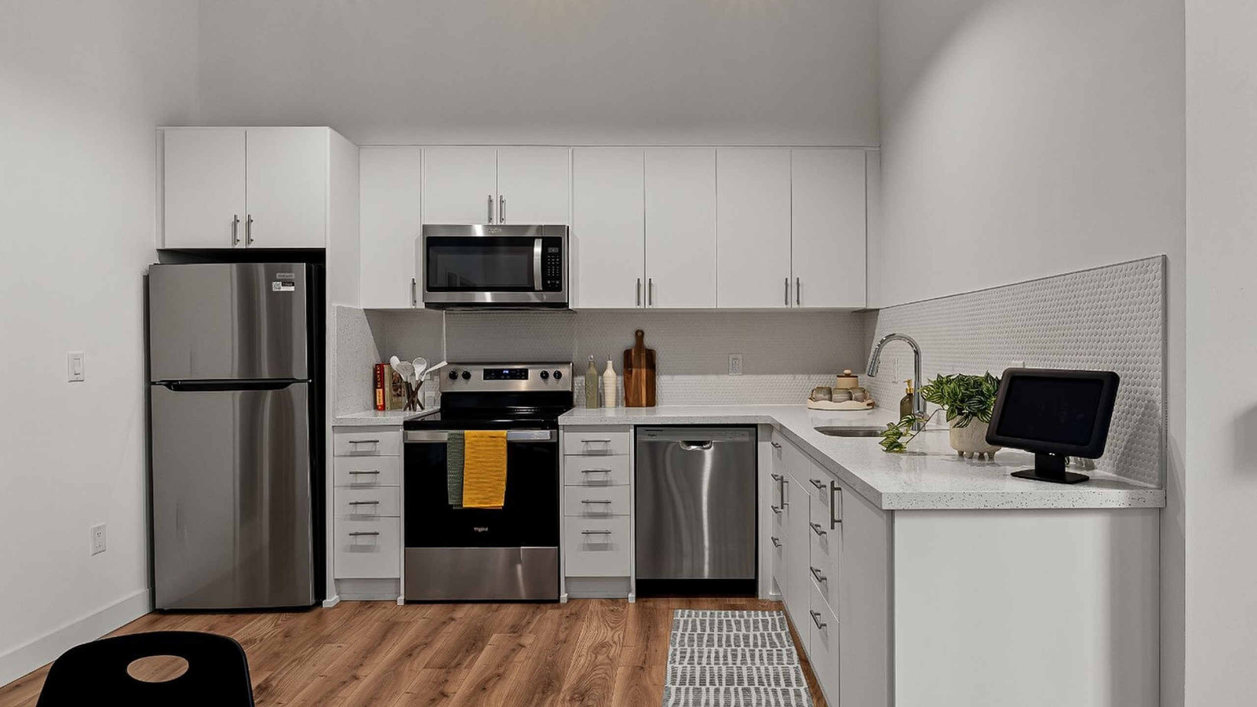 Modern kitchen with sleek stainless steel appliances, elegant white cabinetry, and warm wood flooring creating a stylish and functional space.