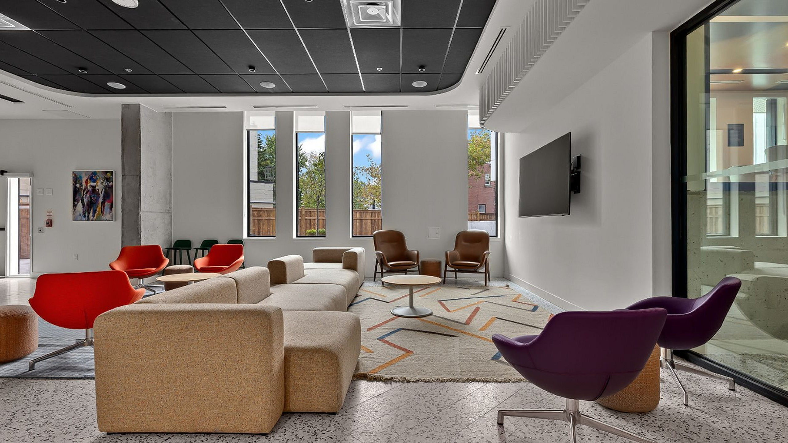 Modern communal lounge with vibrant seating and large windows, offering a cozy and inviting atmosphere.