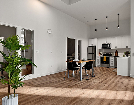 Contemporary open-plan kitchen and dining area with sleek stainless steel appliances, elegant pendant lighting, and warm wooden flooring, creating a welcoming space for modern living.