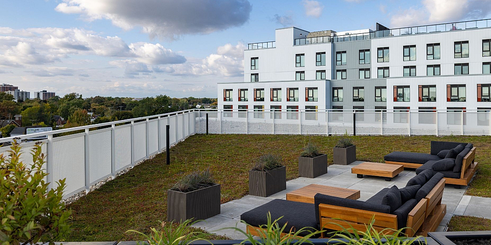 Modern apartment building with a lush rooftop garden and stylish outdoor seating, offering breathtaking city views.