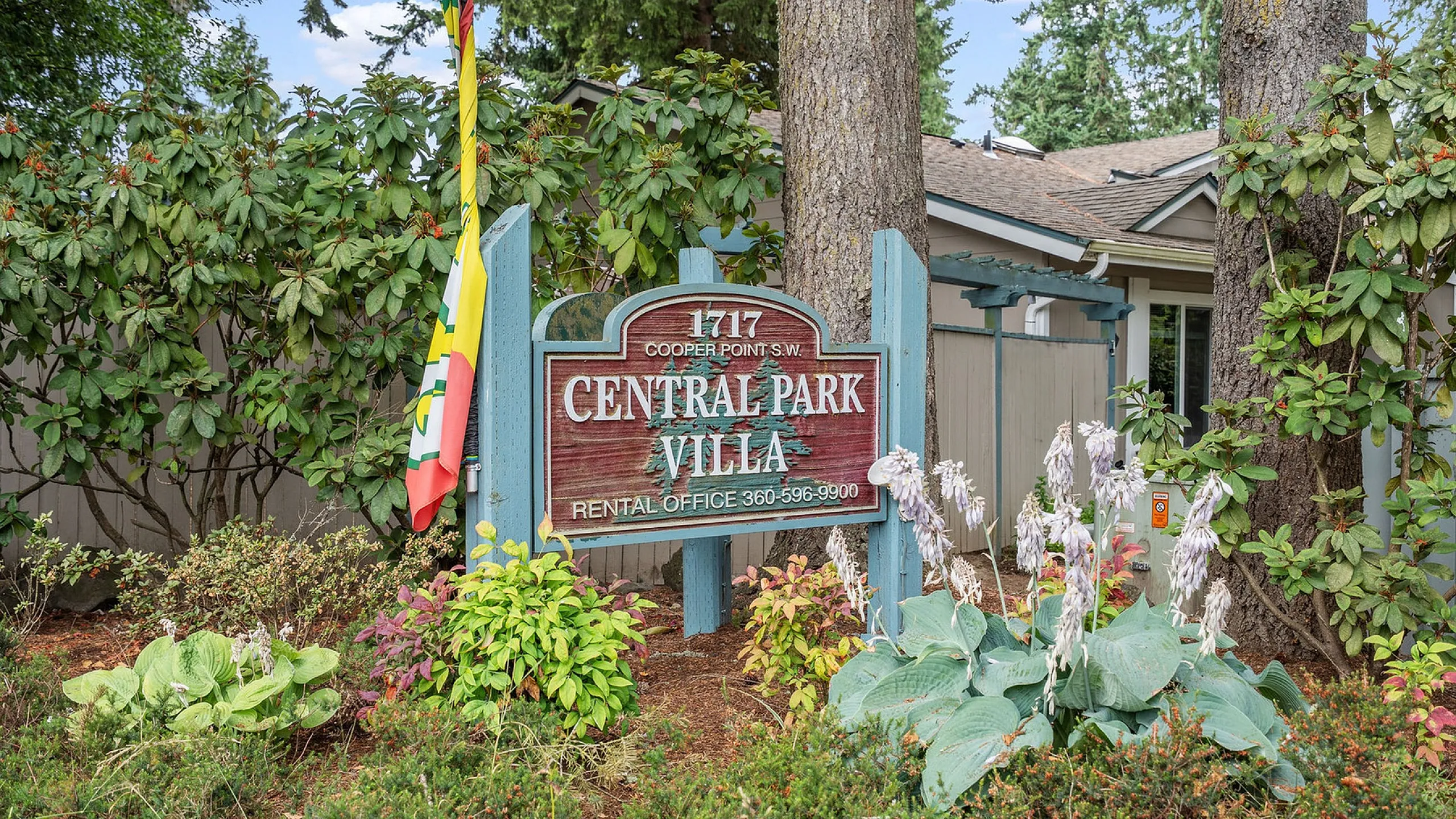 Welcoming entrance to Central Park Villa, beautifully surrounded by lush greenery and vibrant flowers.