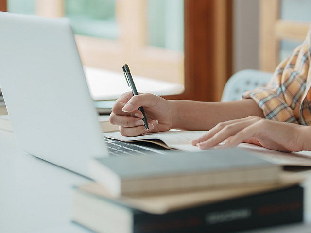 Cozy home workspace with natural light, featuring a person working on a laptop, surrounded by books for inspiring productivity.