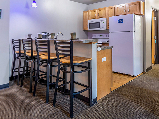 Modern kitchen with sleek appliances and a stylish breakfast bar adorned with wooden stools, ideal for casual dining and entertaining.