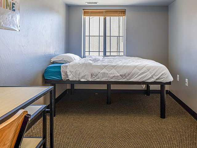Cozy bedroom with a comfortable twin bed, large window for natural light, and a stylish study area.