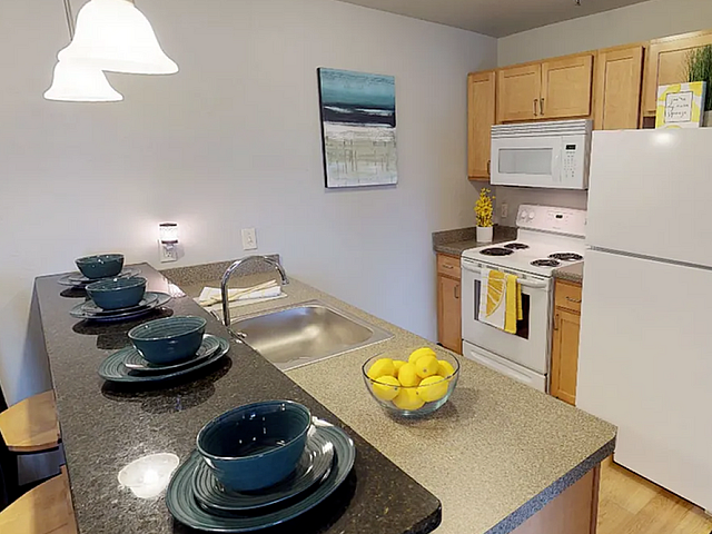 Modern kitchen with sleek countertops, stylish bar seating, vibrant dishware, and bright white appliances, perfect for entertaining.