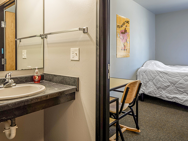 Inviting apartment interior featuring a sleek bathroom with a modern sink and a cozy bedroom with a desk and chair.