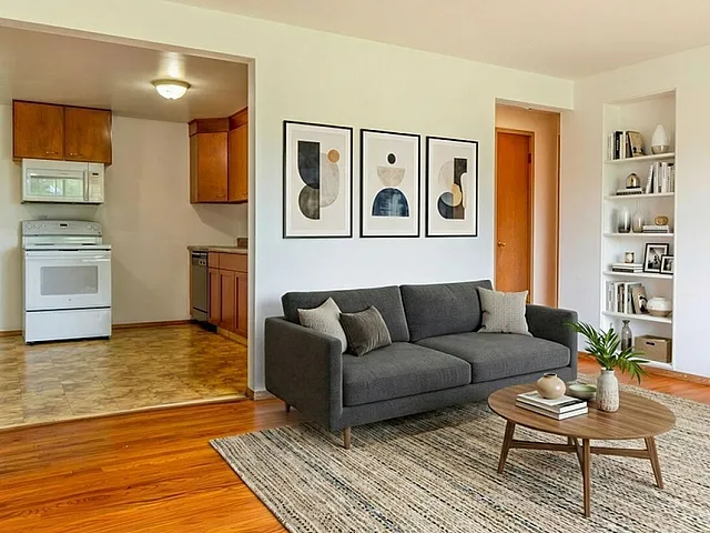 Chic living room with plush gray sofa, modern art, and open kitchen layout, perfect for stylish urban living.