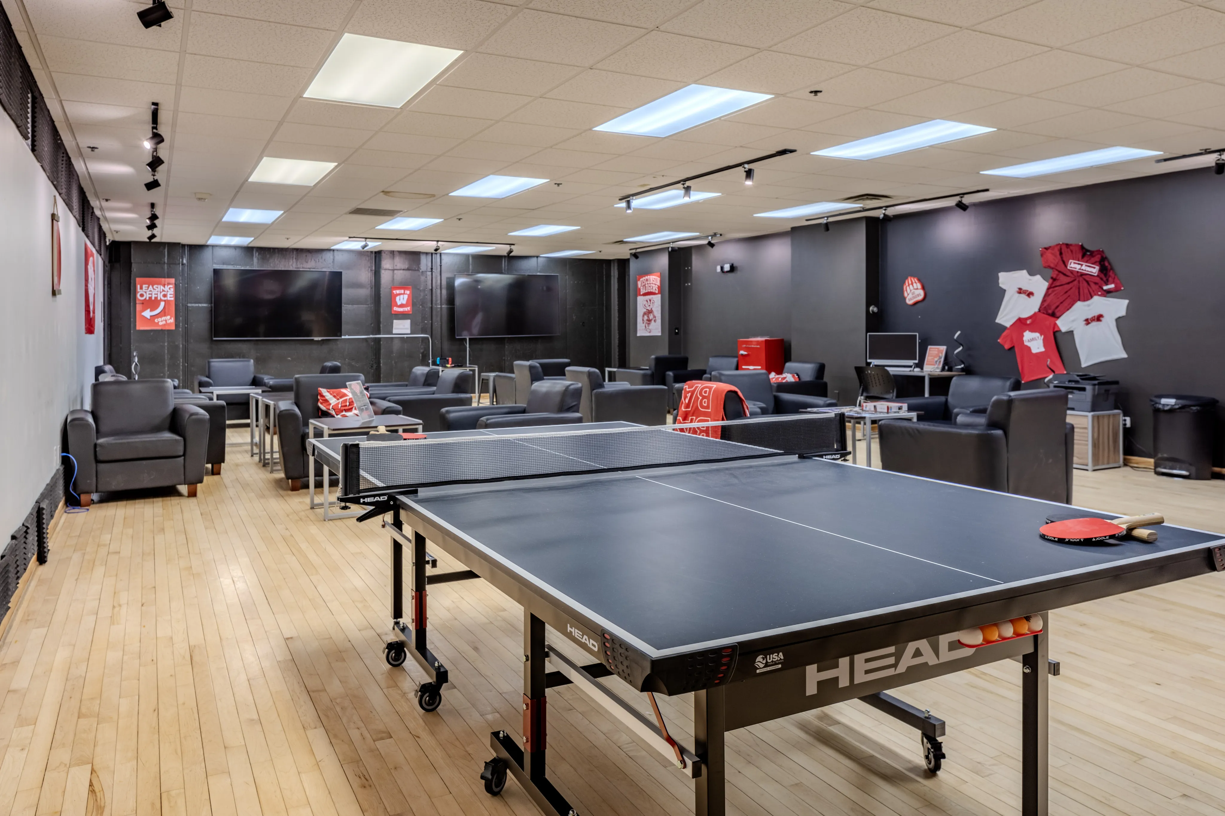 Modern recreation lounge with ping pong table, comfortable seating, and multiple flat-screen TVs.