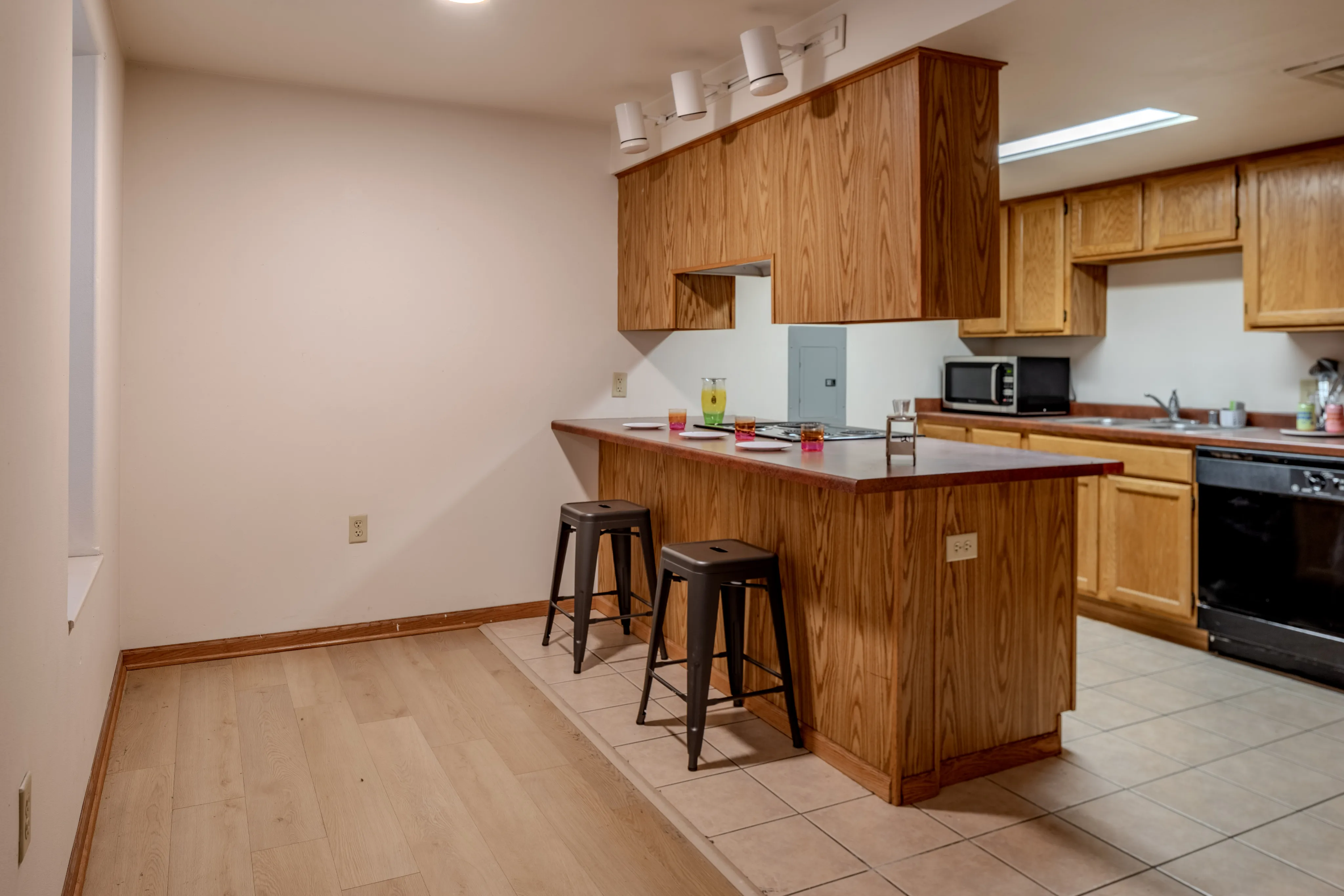 Warm kitchen area with wooden cabinets, a breakfast bar with two stools, and modern appliances.