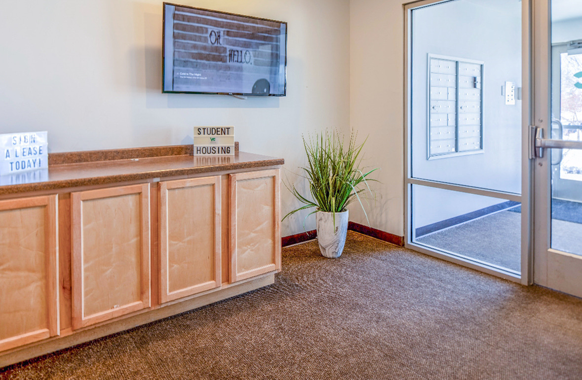 Cozy lobby area with a wooden cabinet, modern decor, and a large window letting in natural light.