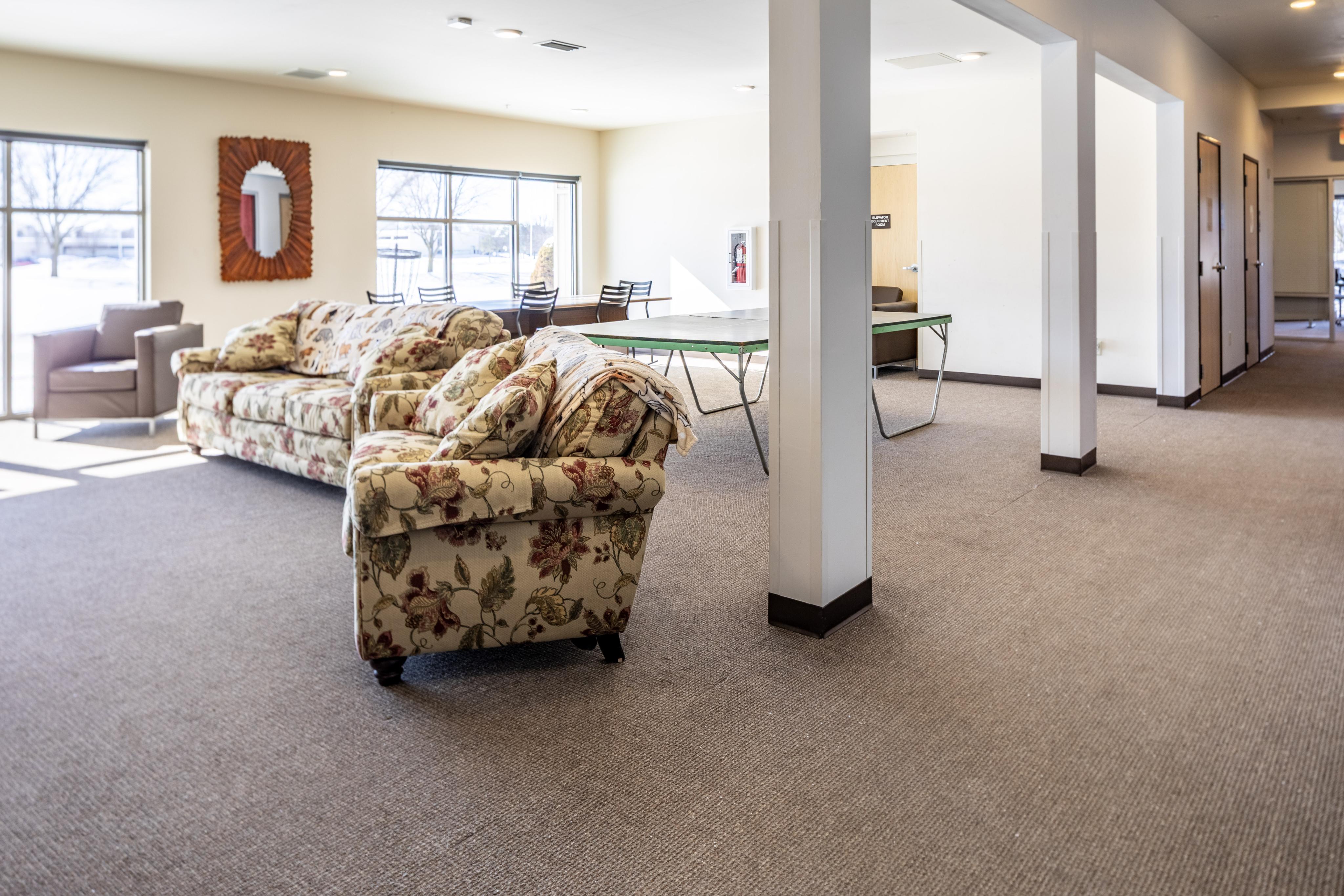 Inviting open living area with floral couches, large windows, and a table for gatherings.