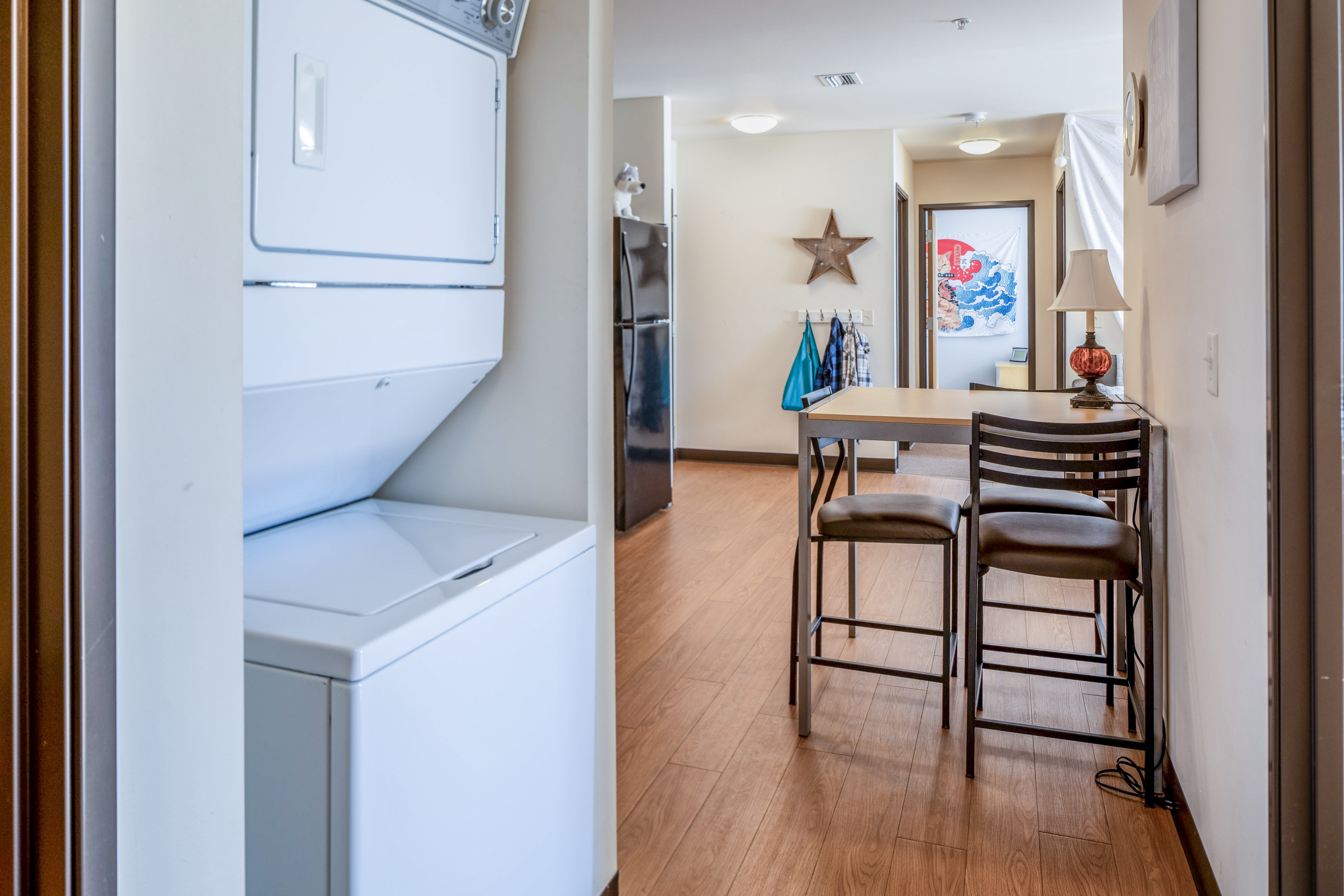 Stylish apartment hallway featuring in-unit laundry, dining area with modern furnishings, and artistic decor.