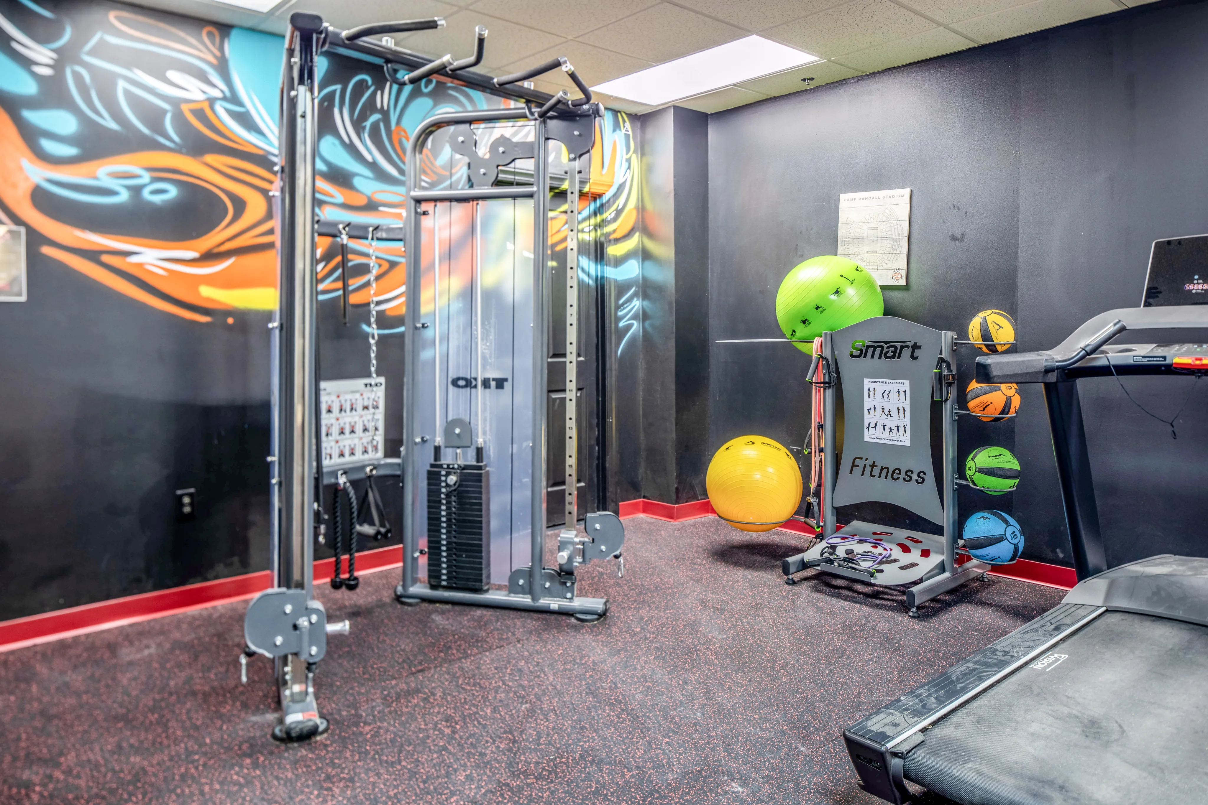 Modern fitness room featuring colorful gym equipment, sleek machines, and motivational art on the walls.