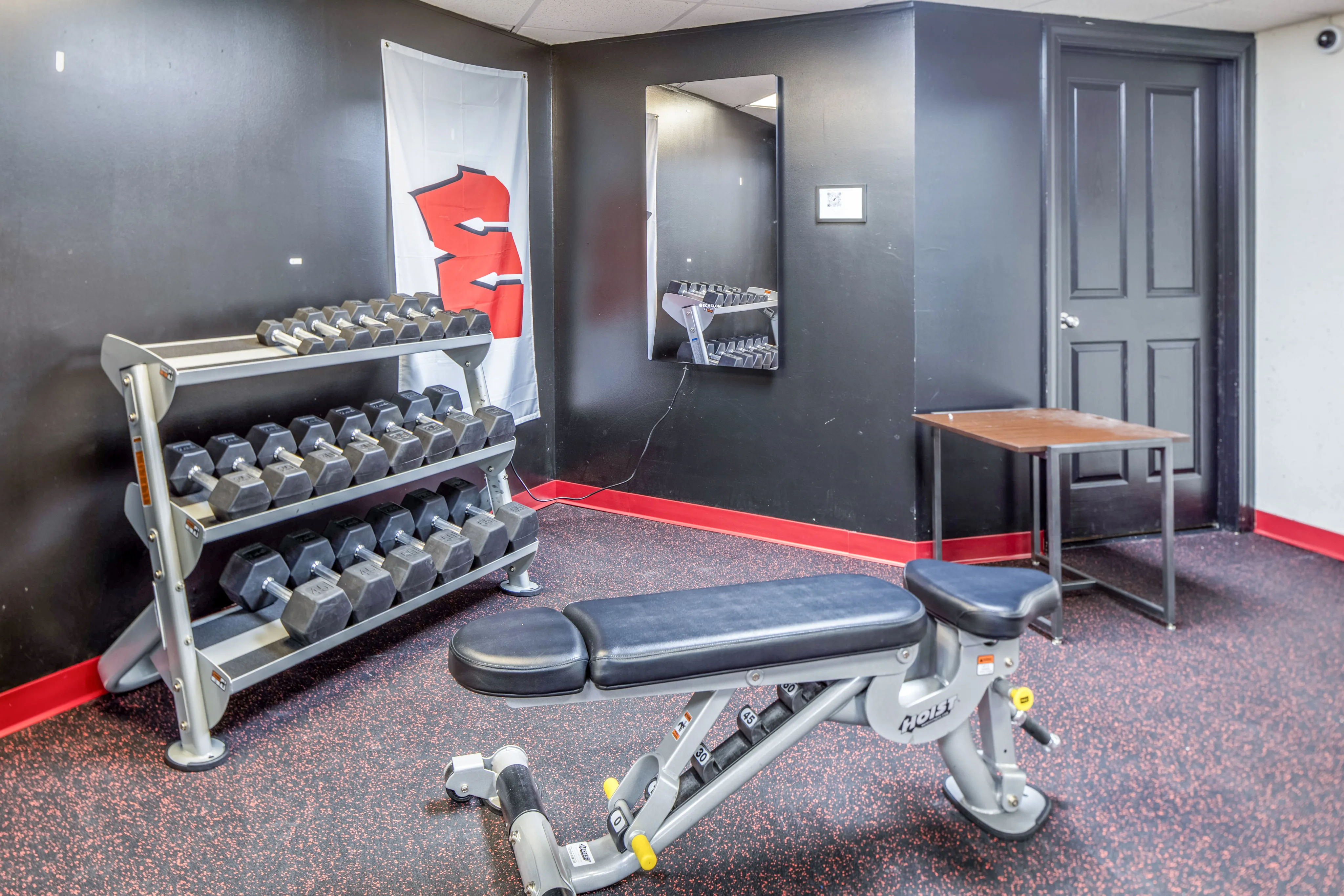 Contemporary gym with dumbbells and an adjustable bench in a sleek, black-accented space.
