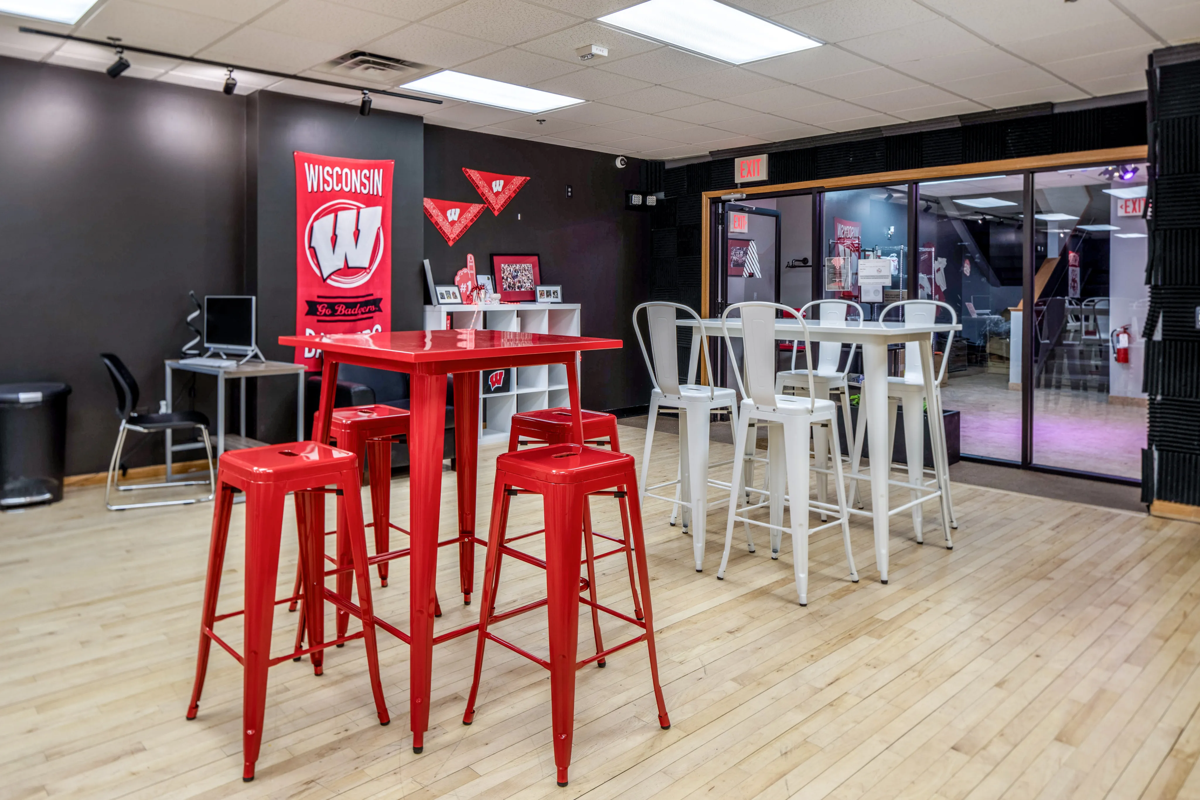 Bright lounge area with red and white bar tables and stools, featuring university-themed decor.